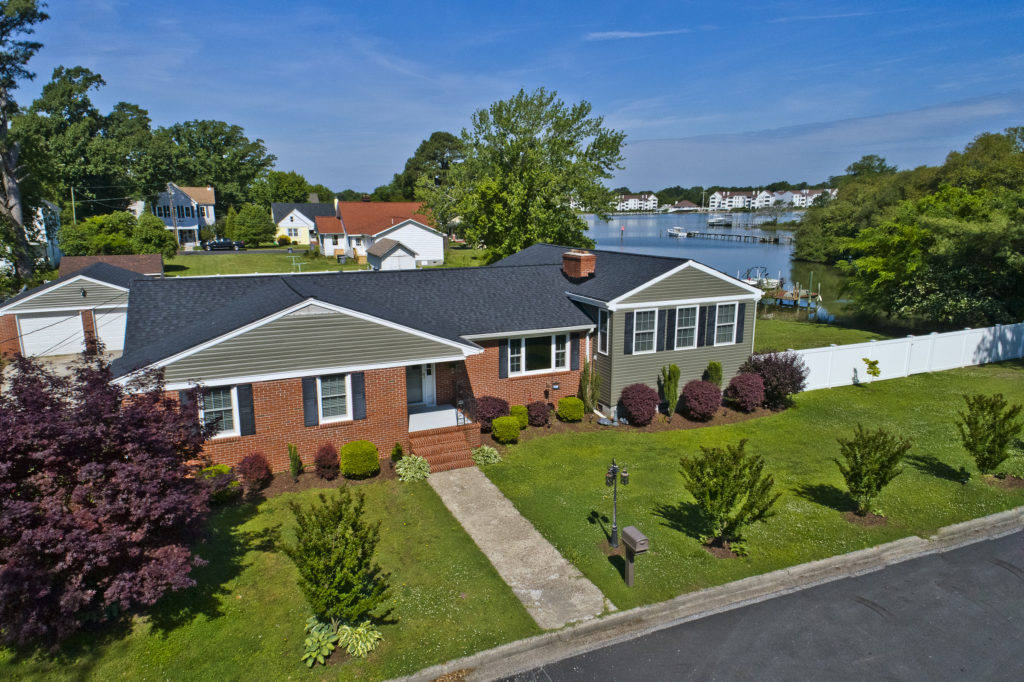 A house with a large yard and water in the background.