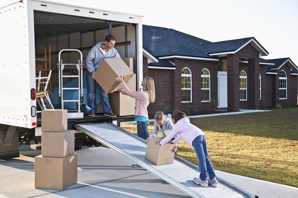 A family unloading boxes from the back of a moving truck.