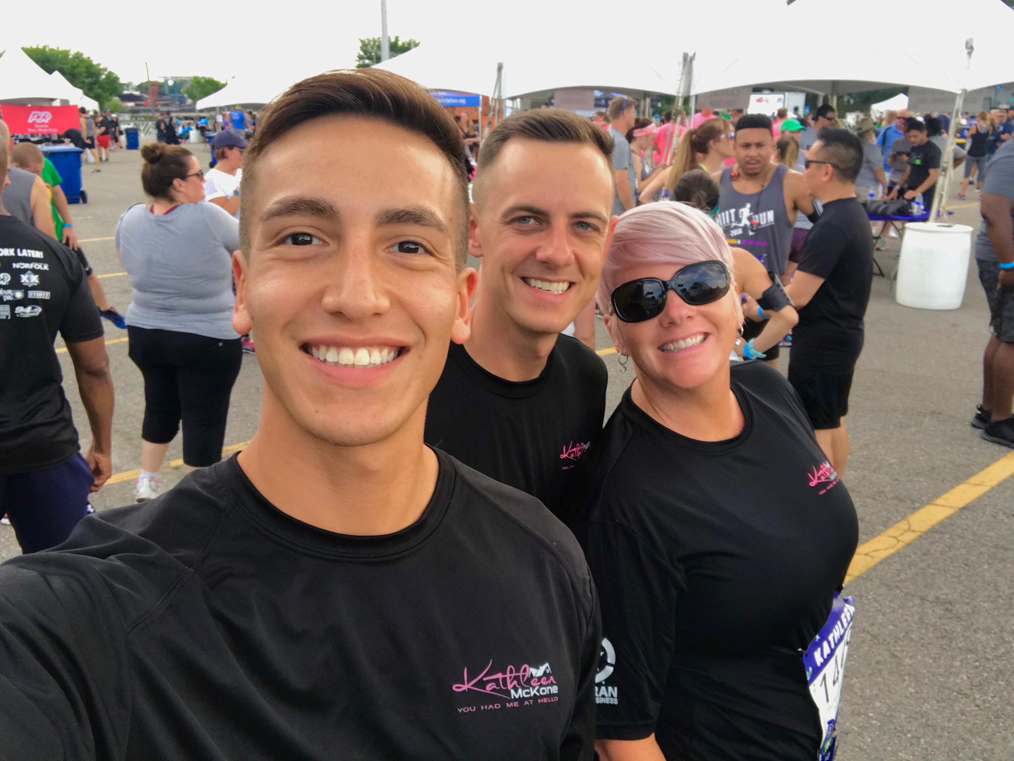 Three people are smiling for a picture in front of a crowd.