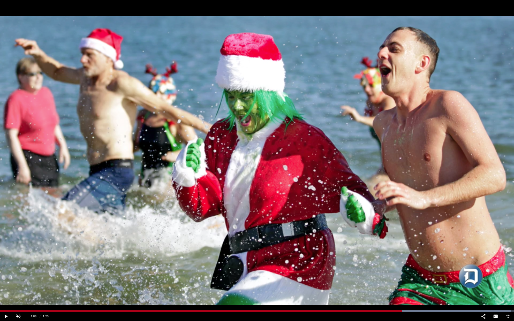 A group of people in the water with santa hats on.